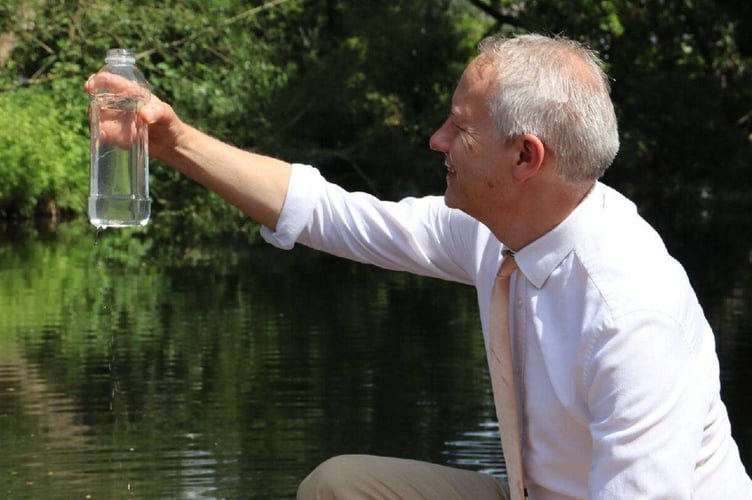 MP Gideon Amos takes a water sample from the River Tone.